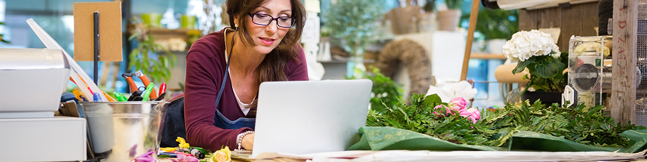 Vrouw in haar eigen bloemenzaak met laptop