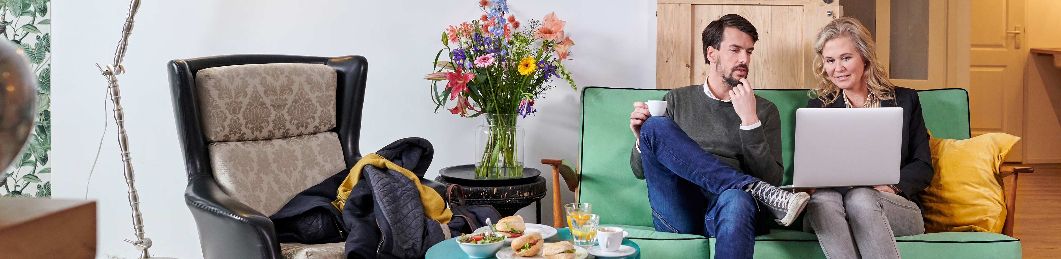 Man en vrouw staren naar en laptop op een loveseat